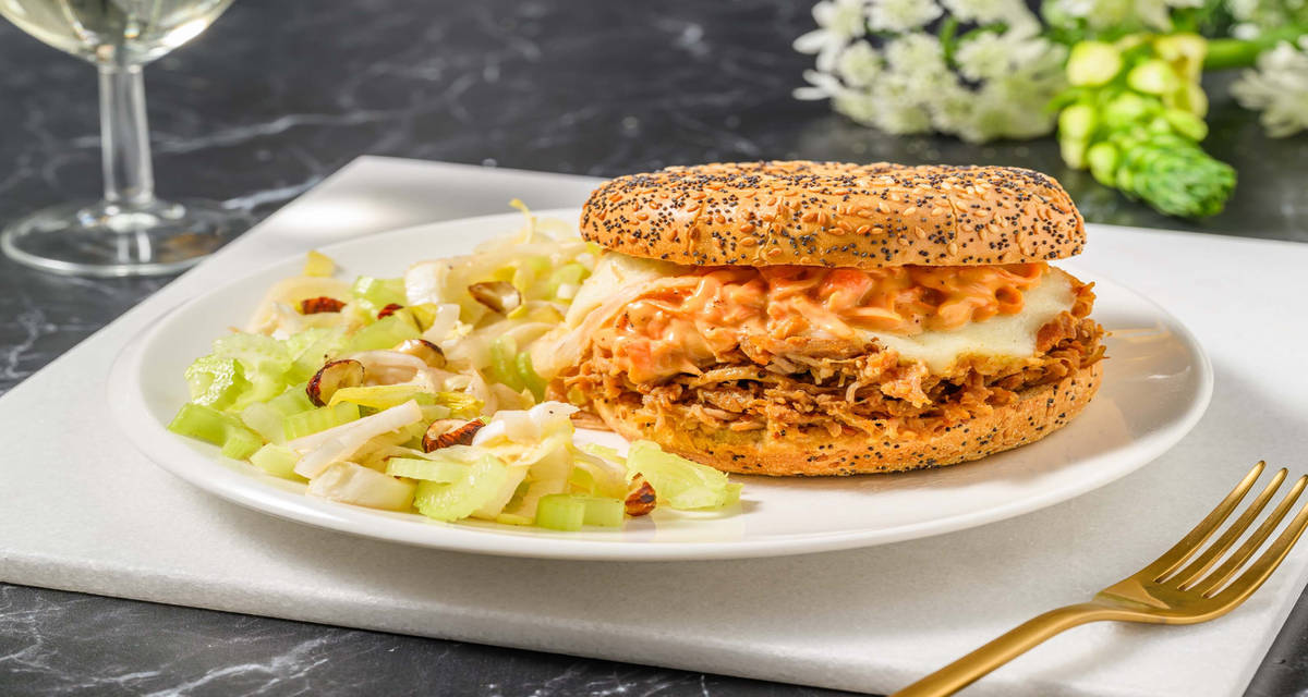 Bagel ricco al pulled chicken e formaggio affumicato con carote in salsa rosa, indivia e nocciole