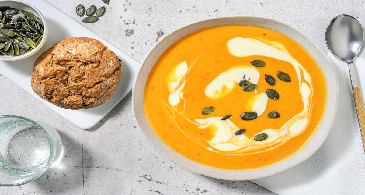 Hartige zoete-aardappelsoep met crème fraîche, bierbostelbroodje en pompoenpitten