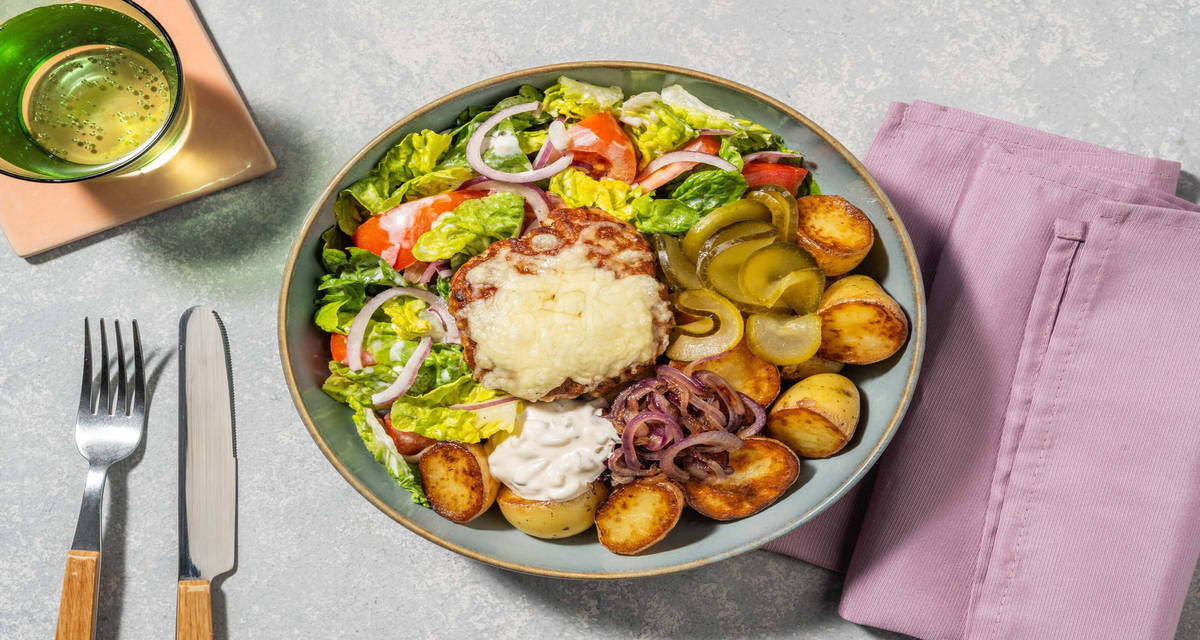 Cheeseburgerbowl met patatjes met salade, augurken en gebakken ui