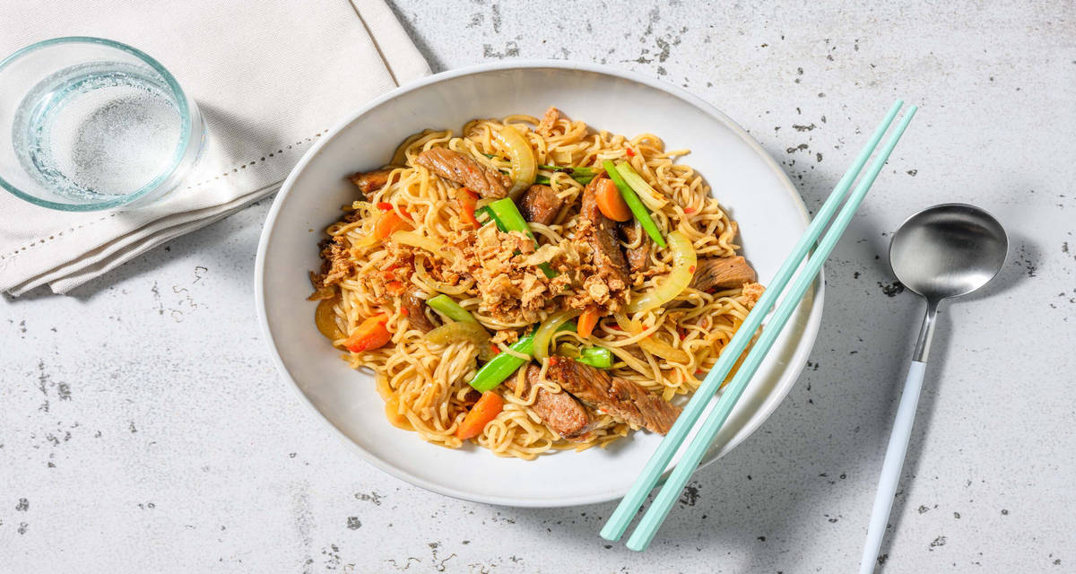 Stir-fry met biefstukreepjes en volkoren noedels met woksaus met gember, groenten en gefrituurde uitjes