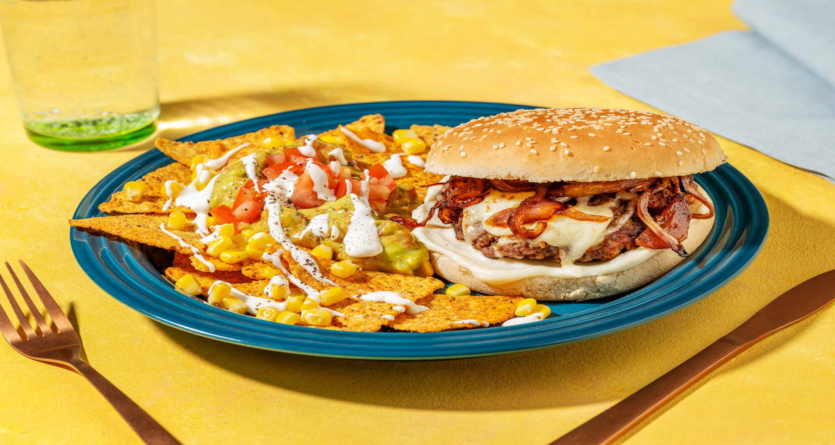 Cheeseburger et chips de tortilla garnies avocat, mayonnaise épicée, maïs et tomate