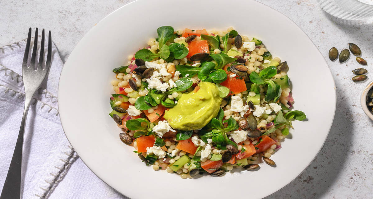 Salade de couscous perlé, guacamole et fromage à la grecque tomate, herbes fraîches et graines de courge