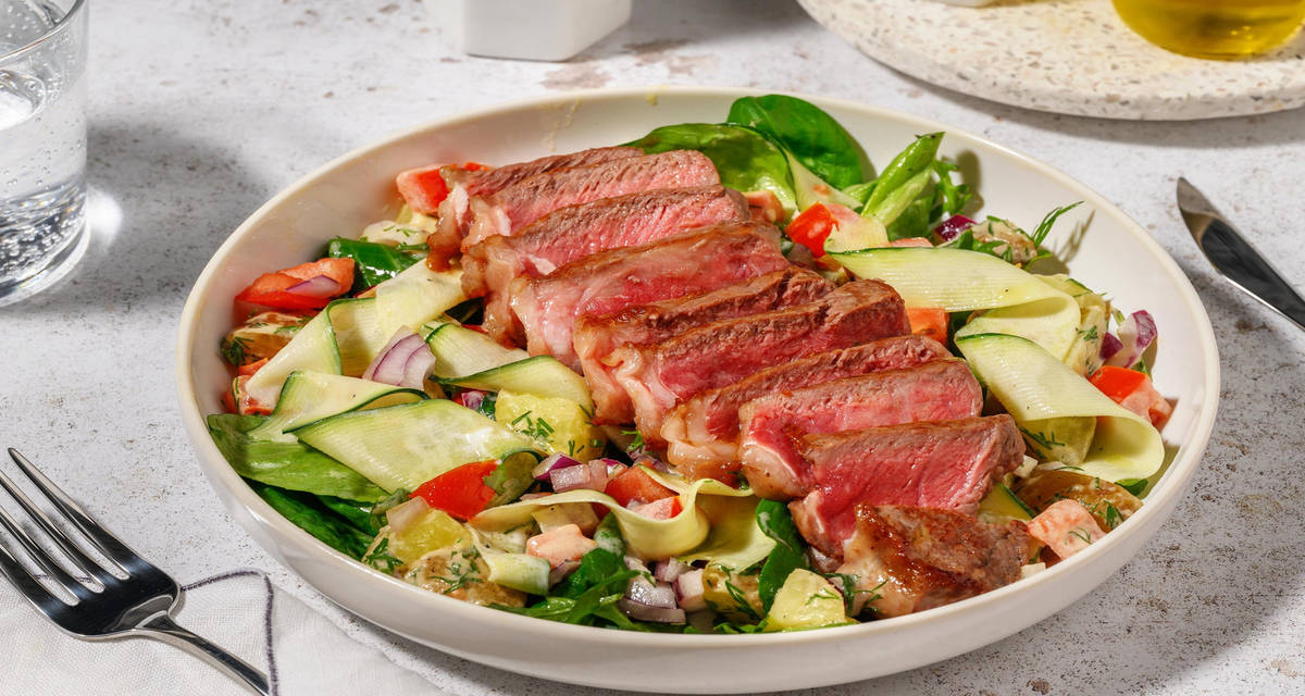 Steak met salade van courgettelinten met rucola, patatjes, tomaat en dille