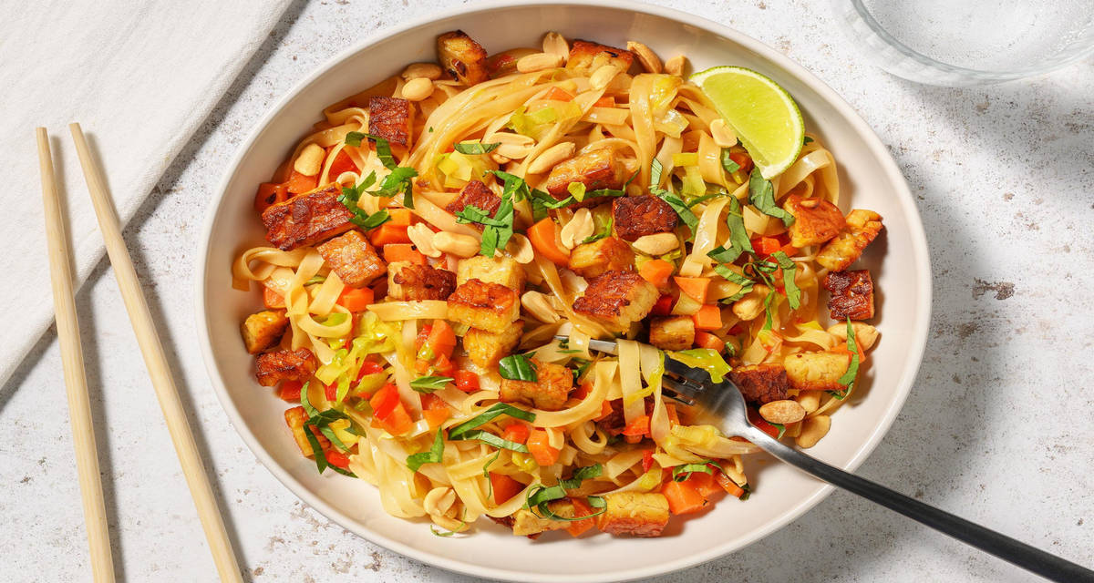 Kruidige Thaise-stijl noedelbowl met tempeh met limoen, pinda's en verse kruiden