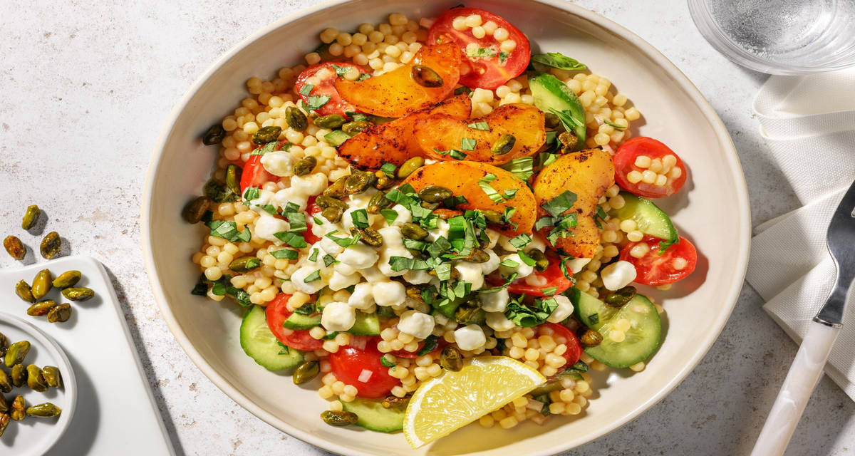 Salade met gegrilde nectarine en honing-geitenkaasbolletjes met geroosterde pistachenoten, parelcouscous en basilicum-citroendressing