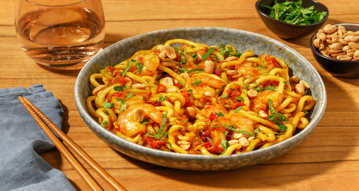 Udonnoedels met scampi's in zoete Aziatische saus met pinda's, verse kruiden en gebakken groenten