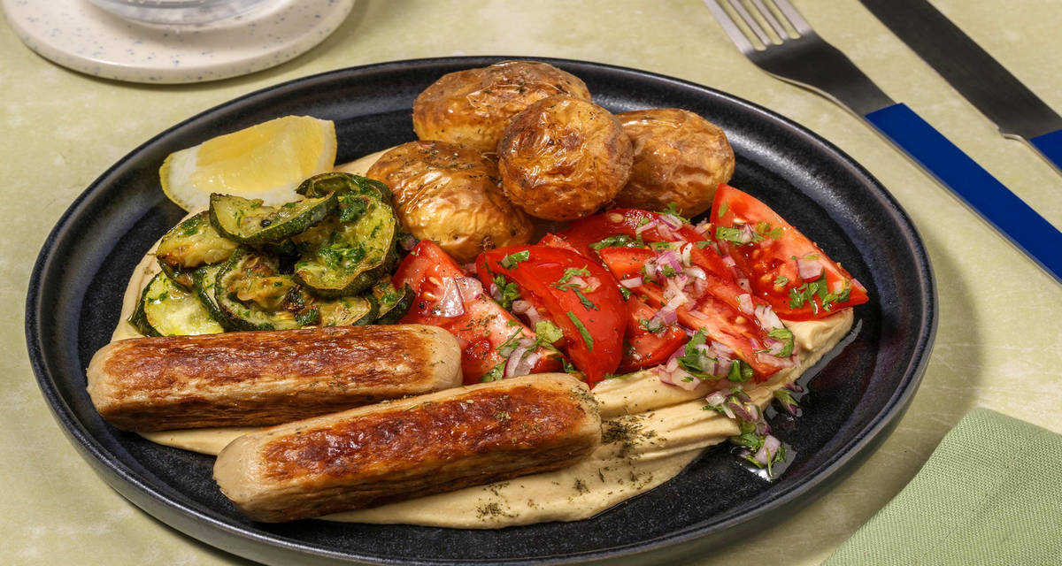 Mezzeschotel met kipworstjes en zhoug-courgette met patatjes, hummus en tomatensalade