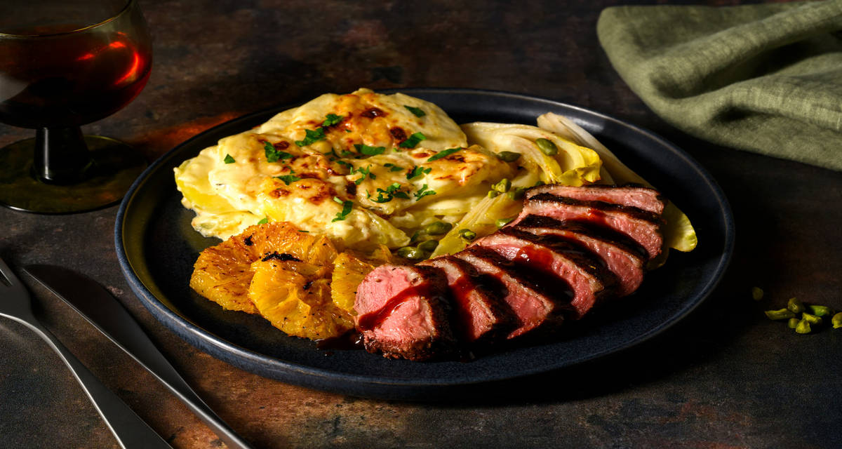 Magret de canard en sauce à l'orange & vin rouge chicon, gratin de pommes de terre crémeux et pistaches