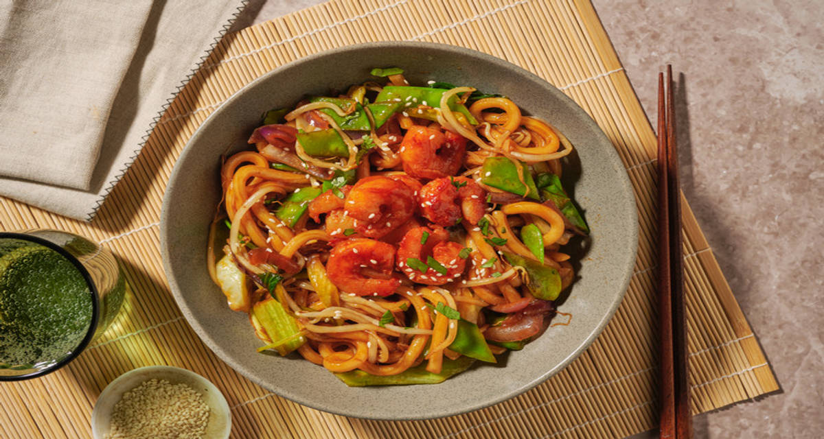 Stir-fry met scampi's, udonnoedels en zoete Aziatische saus met groenten op z'n Thais, koriander en sesamzaadjes