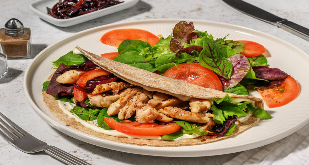 Tortillas integrale farcita di pollo e pomodoro con salsa aioli, insalata e cipolla caramellata