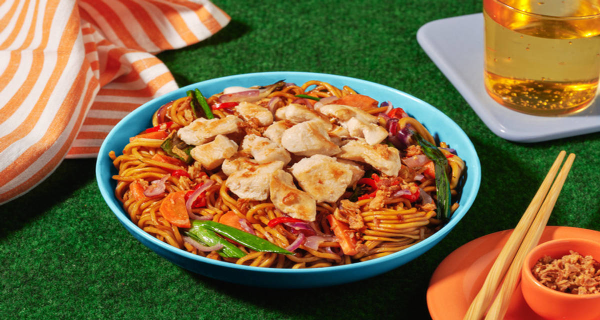 Stir-fry met kip en noedels met gemberwoksaus, groenten en gefrituurde uitjes