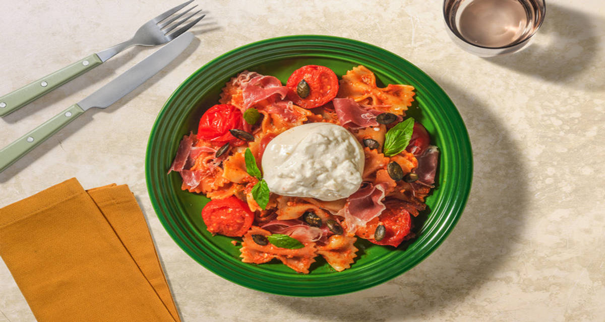 Pasta caprese met prosciutto en burrata met rode pesto en pompoenpitten