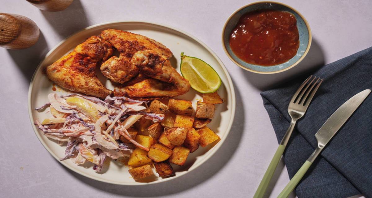 Ailes de poulet à la caribéenne & sauce mangue slaw garni de pomme, citron vert et pommes de terre rôties