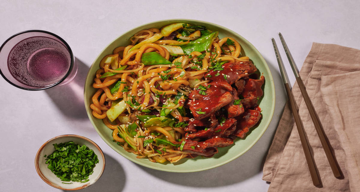 Roerbak met biefstuk, udonnoedels en zoete Aziatische saus met Thaise stijl groenten, koriander en sesamzaadjes