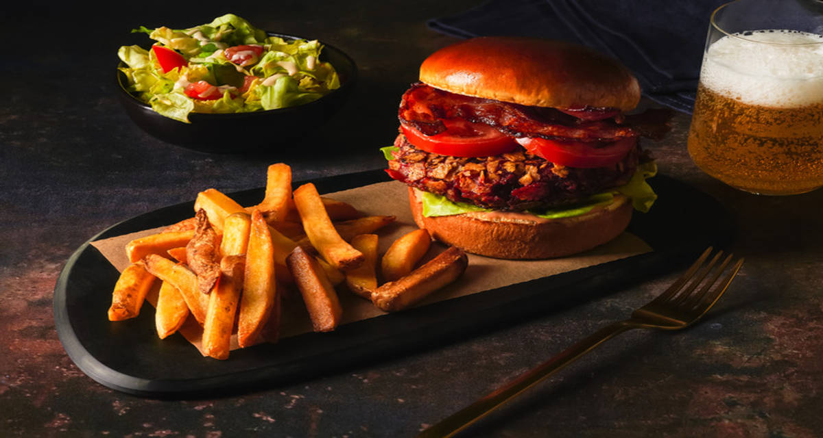 Burger en croûte de betterave au lard sur pain brioché frites, salade de tomate et concombre et sauce fumée