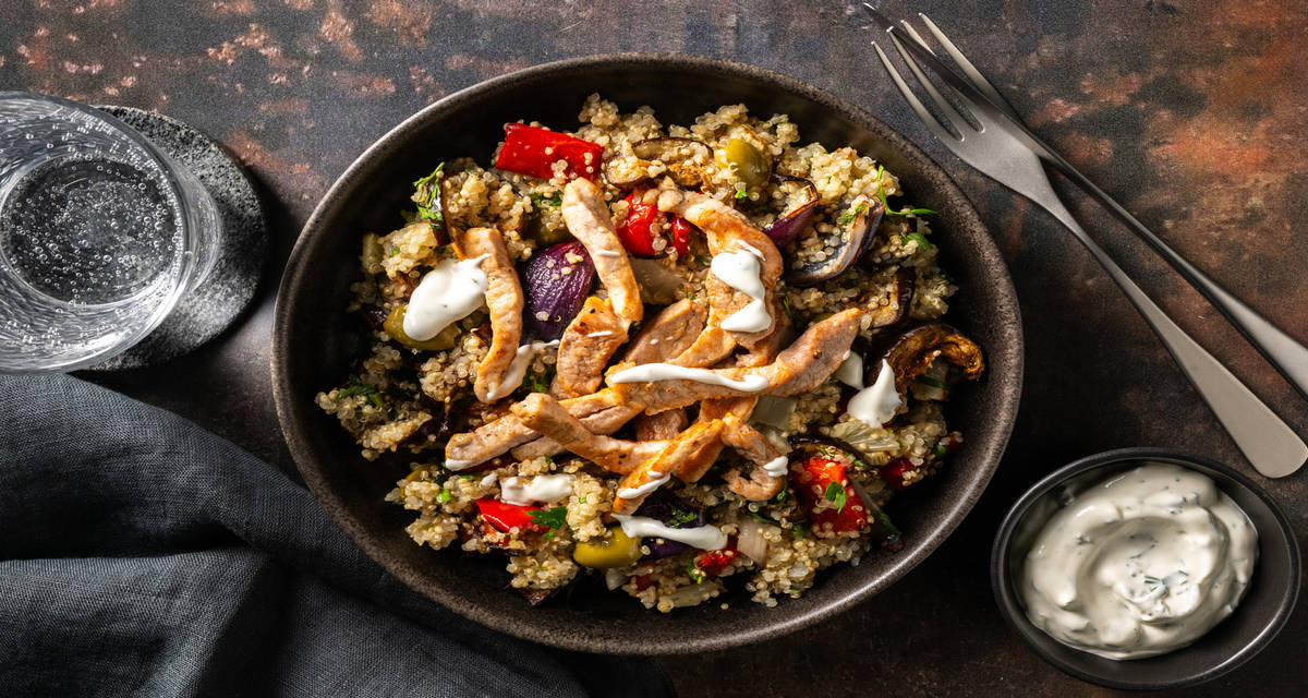 Varkensschnitzel met quinoa en yoghurtsaus met olijven, geroosterde groenten en verse kruiden