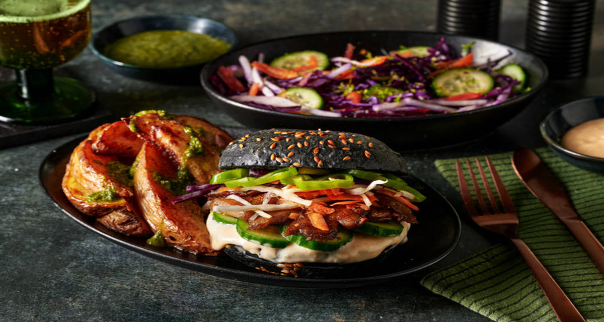 Tandoori-oesterzwamburger met frisse groene chutney op zwart streetfoodbroodje met mangomayonaise en koolsla