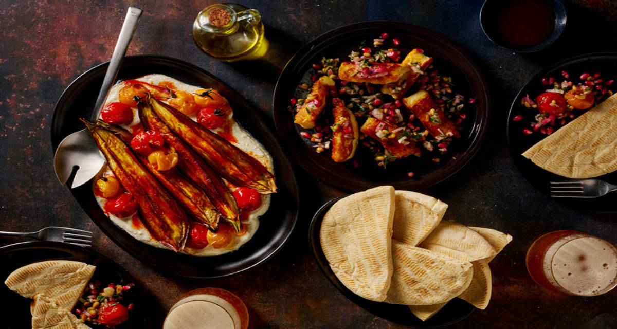 Mezze met halloumi, opgeklopte feta en granaatappel met pijnboompittensalsa, aubergine, pita en tomaten
