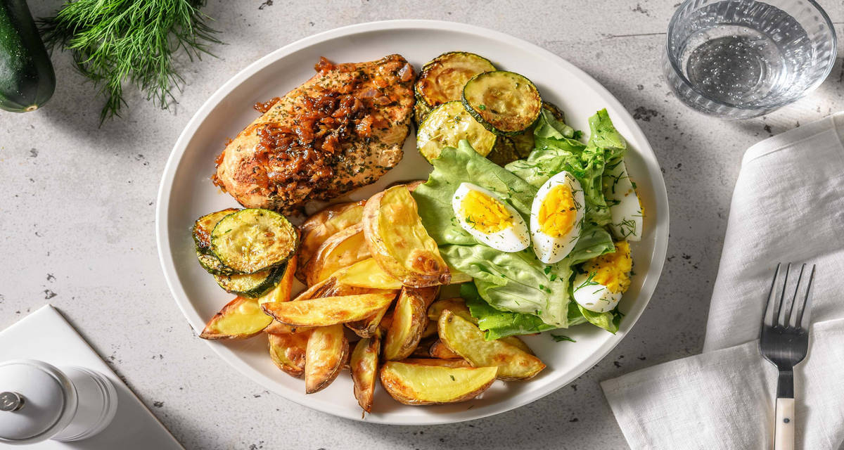 Filet de poulet aux herbes et pommes de terre au four accompagnés d'une salade, de courgette grillée et d'un œuf dur