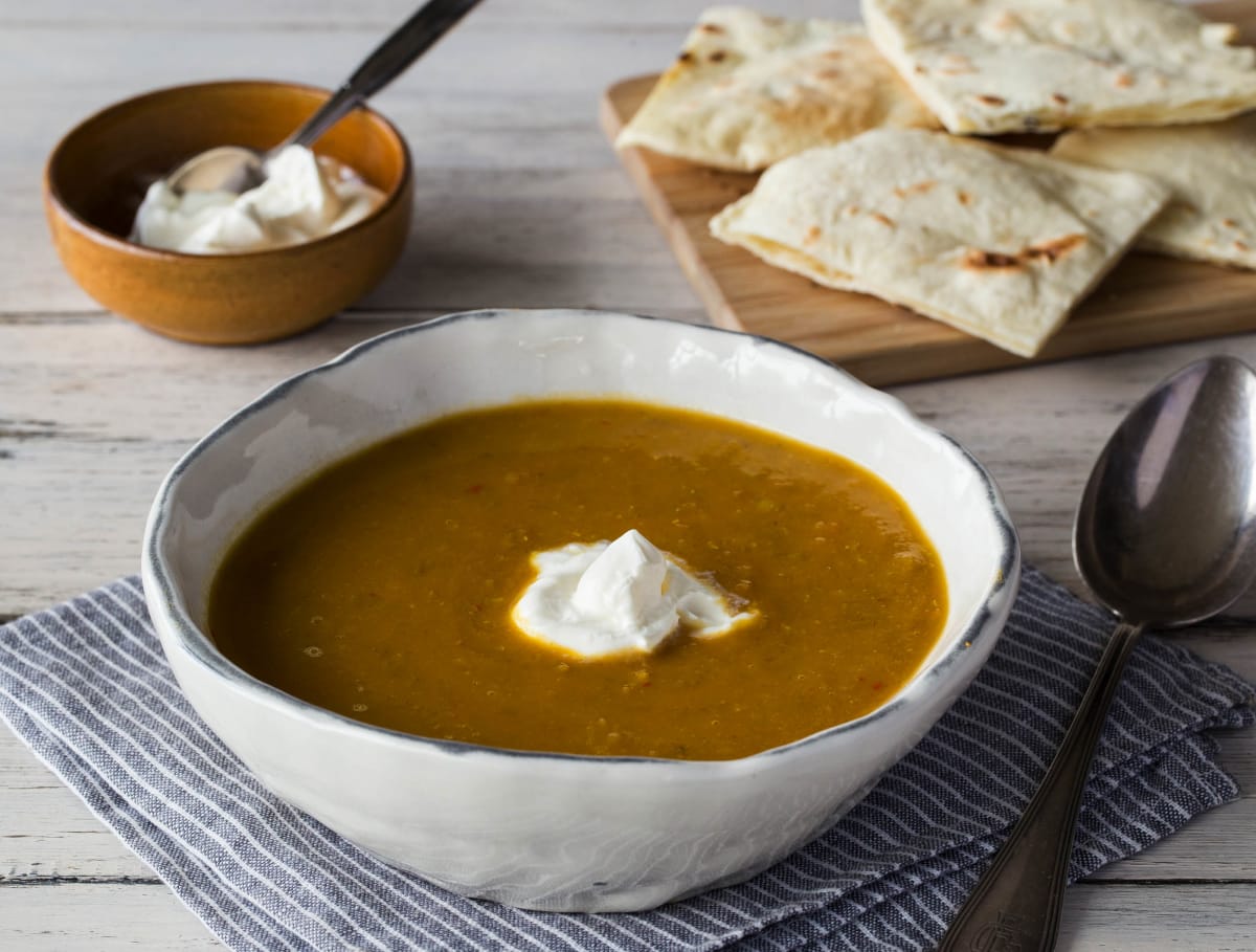 Zoete wortel–linzensoep met crème fraîche en naanbrood