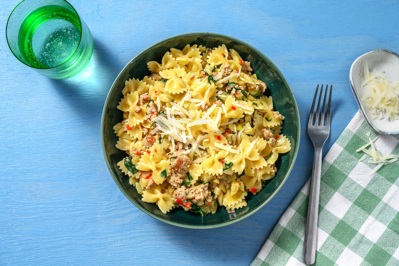 Farfalle cremosos con carne picada con espinacas, chili rojo y queso rallado