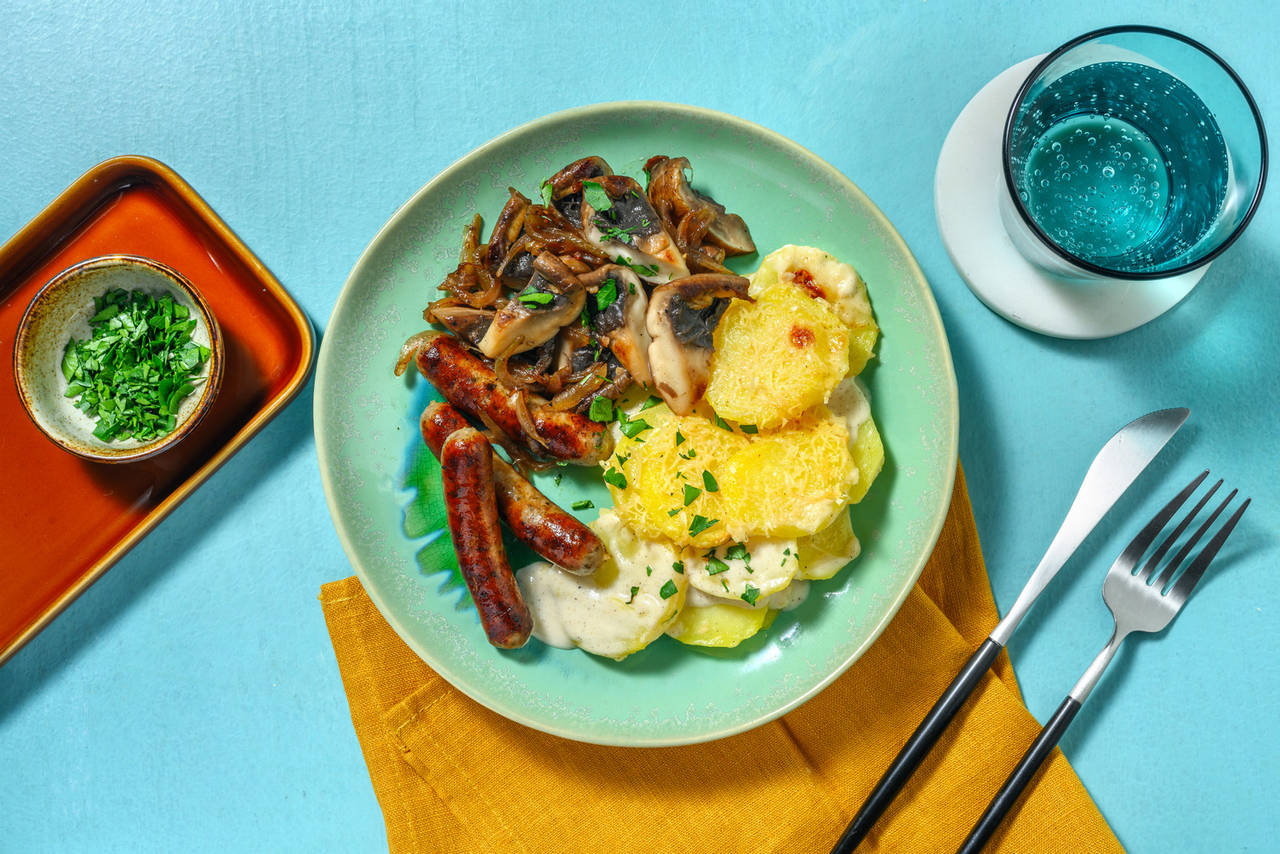 Salchichas con setas portobello y cebolla acompañadas de pastel de patata gratinado y perejil