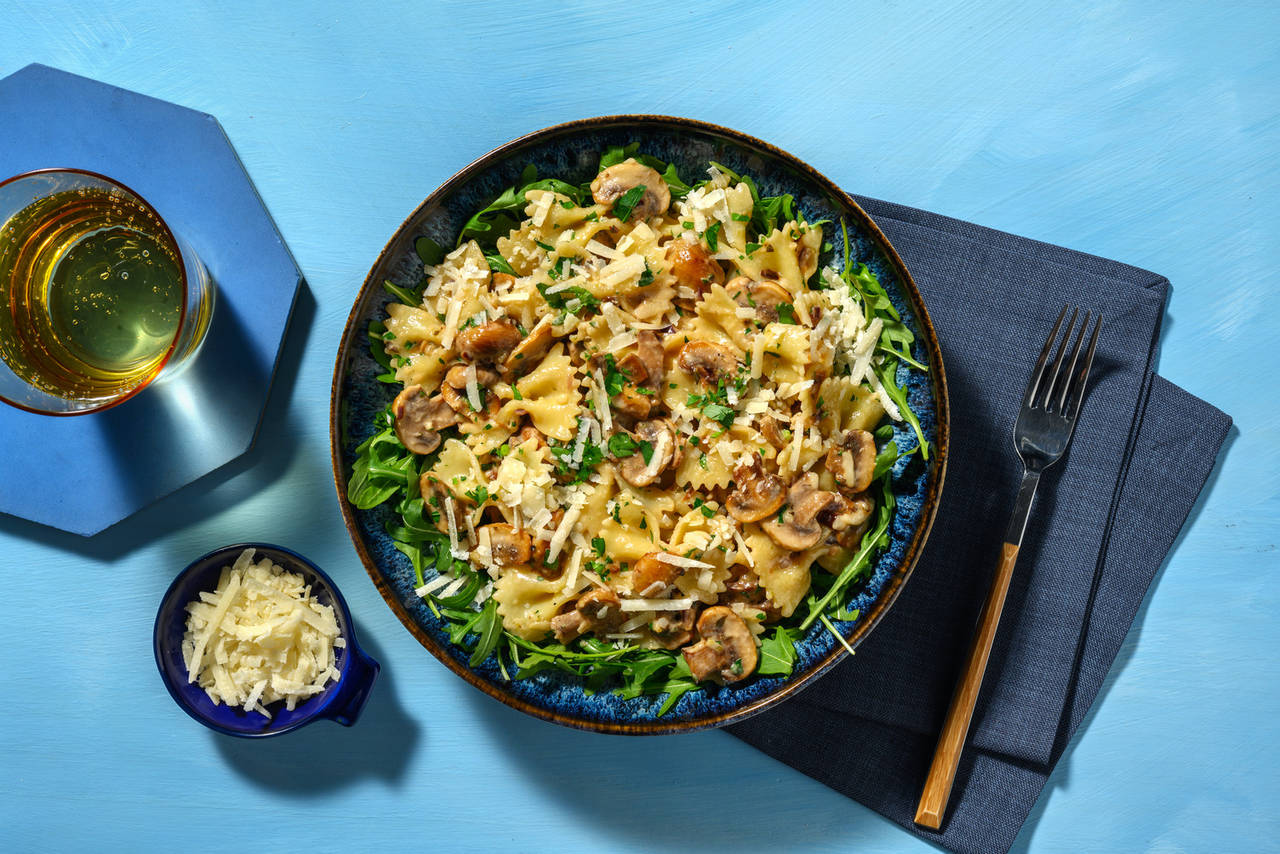 Farfalle con fricasé de champiñones con queso italiano curado y rúcula