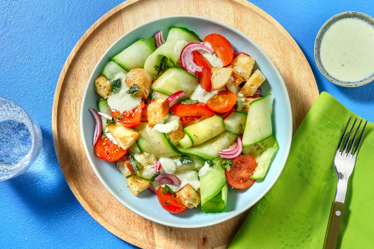Ensalada griega de tomate y pepino con cebolla encurtida, picatostes y salsa de queso griego