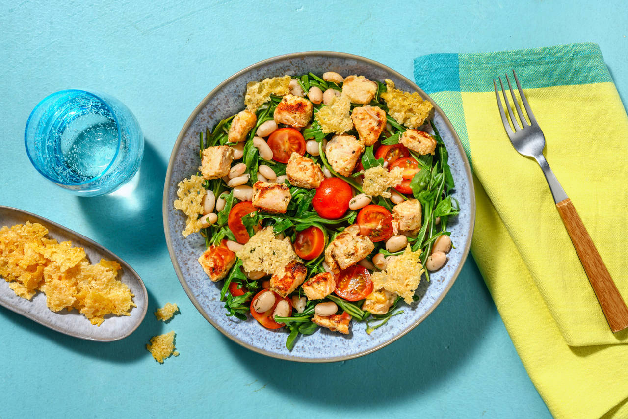 Dados de salmón con crujiente de queso sobre ensalada de rúcula, cherrys y judías blancas