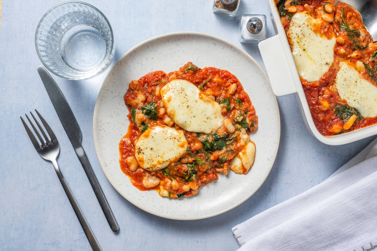Gratinado de alubias con mozzarella fundida con espinacas y salsa casera de tomate