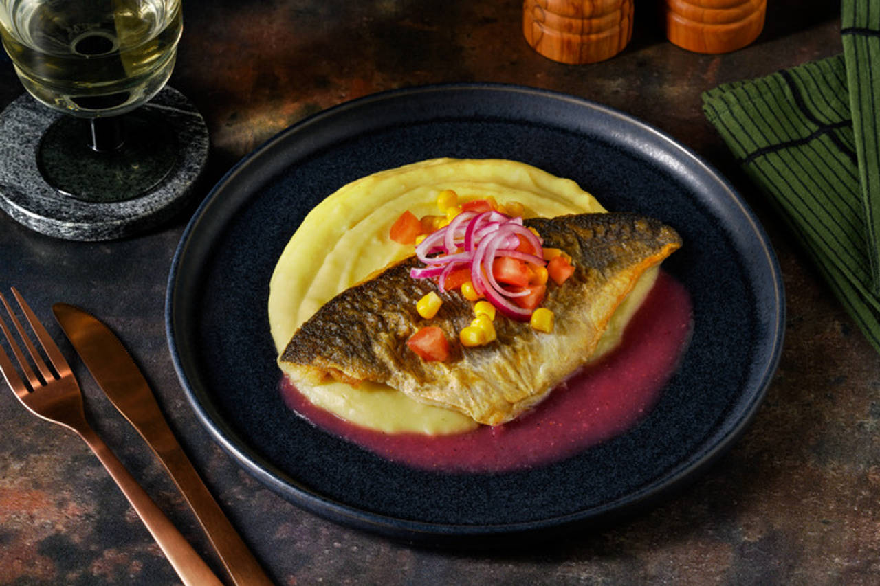 Lubina con salsa cítrica rosada y cebolla encurtida con tomate, maíz y parmentier de patata y chirivía
