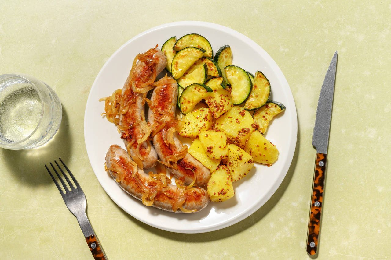 Salchichas encebolladas con patatas a la mostaza con calabacín salteado