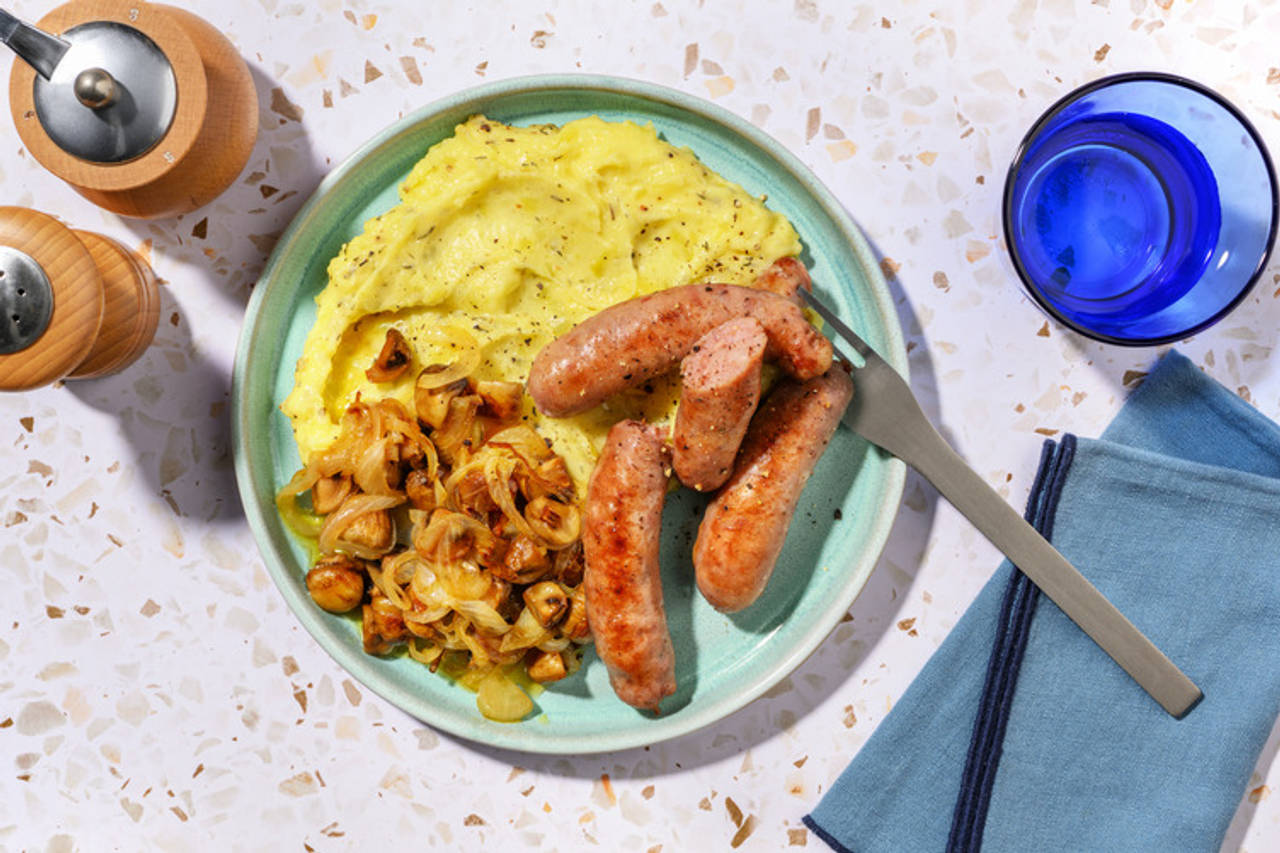 Salchichas de pollo acompañadas de puré al tomillo con champiñones salteados