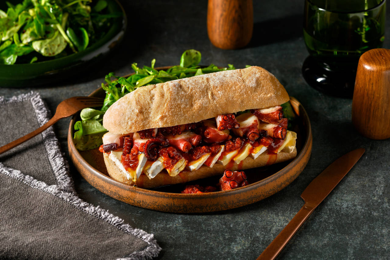 Bocadillo de pulpo con sobrasada, camembert y miel con ensalada de rúcula y canónigos