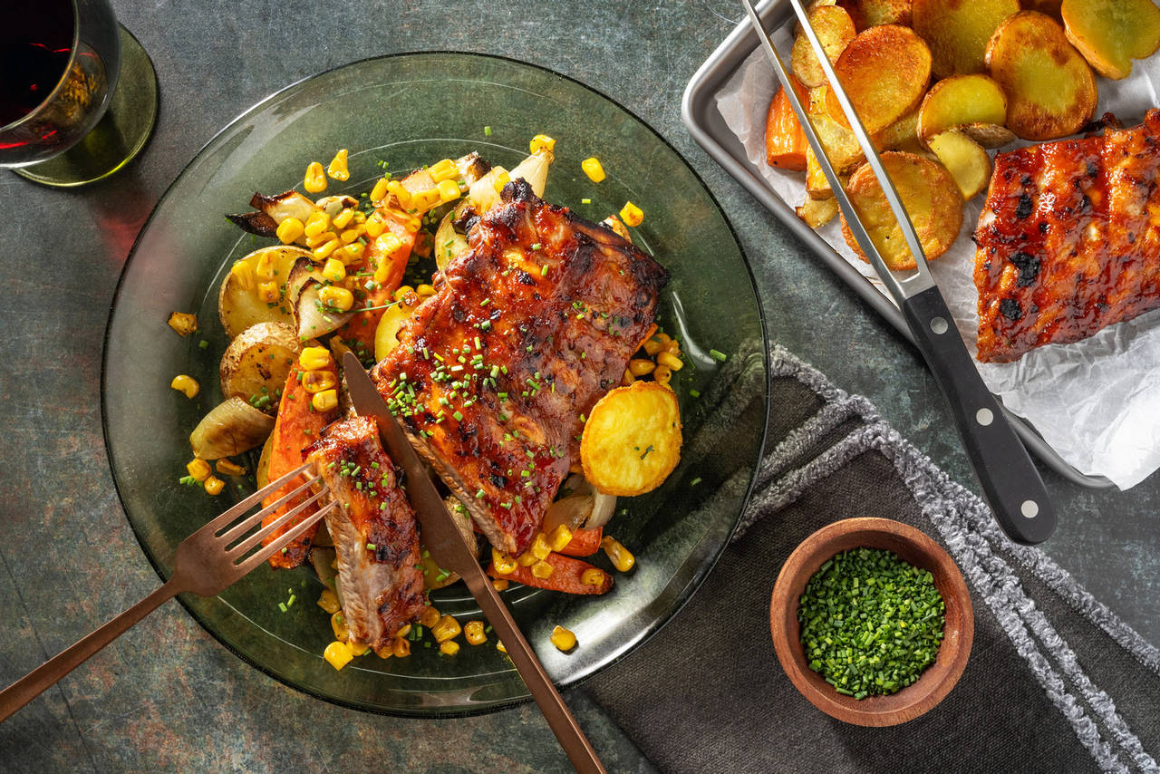 Costillas de cerdo a la barbacoa con patatas y verduras asadas y maíz tostado