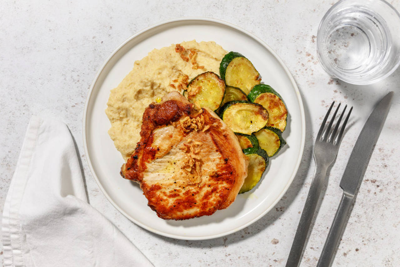 Extra de chuleta de cerdo con puré de coliflor caramelizada con láminas de calabacín y cebolla frita