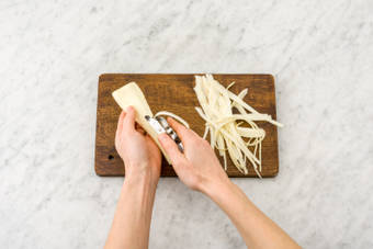 Schil de pastinaak met een dunschiller of kaasschaaf en schaaf in lange linten.