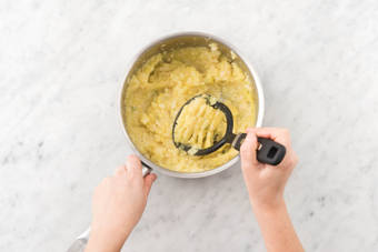 Stamp de aardappelen, knolselderij en tijm tot een grove puree met een aardappelstamper.