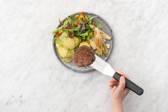 Servir les chicons, les pommes de terre et les steaks hachés sur les assiettes et accompagnez-les de la salade.