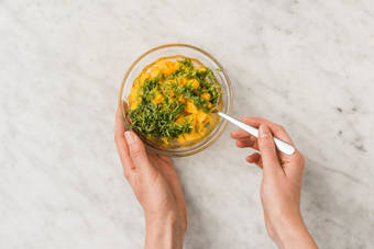 Wasche Gemüse und Kräuter ab.  Zum Kochen benötigst Du 2 kleine Schüsseln, 1 kleinen Topf, 1 große Pfanne, 1 Sieb, 1 Knoblauchpresse und 1 große Schüssel.  Erhitze reichlich **Wasser** im Wasserkocher.  **Mango** schälen, Fruchtfleisch vom Kern schneiden und in 1 cm große Würfel schneiden. **Mangokern** beiseitestellen.  Blätter der **Minze** abzupfen und fein hacken.  In einer kleinen Schüssel **Mangowürfel** mit gehackter **Minze** und 1 EL [1.5 EL | 2 EL] **Olivenöl**\* verrühren und marinieren lassen.