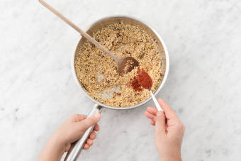 Voeg de quinoa, komijnpoeder en paprikapoeder toe.