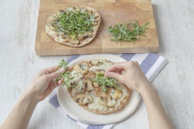Top pizzas with fresh rocket and a bit of olive oil