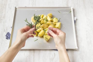 Scatter potatoes on baking sheet with rosemary and olive oil