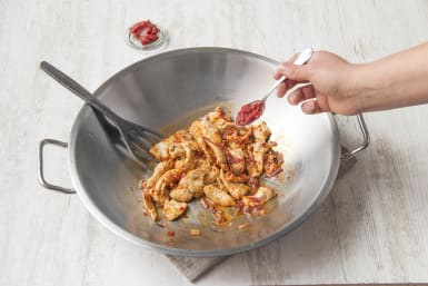 Voeg de tomatenpuree en komijnpoeder bij de kip