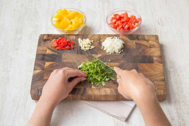 Snijd de ui, knoflook, rode peper en paprika klein