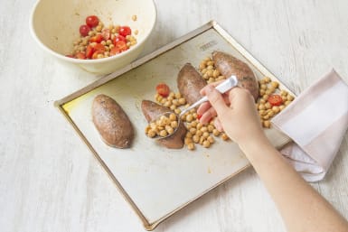 Scatter chickpeas and tomatoes onto sweet potatoes
