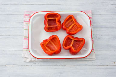 Snijd de paprika doormidden en verwijder de zaadlijsten.