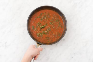 Doe de tomatenpassata en baby spinazie in een pan.