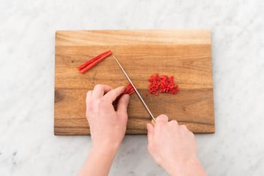 Verwijder de zaadlijsten van de rode peper en snijd de rode peper fijn.