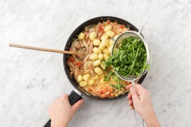 Voeg de gnocchi en rucola toe aan de wok of hapjespan.